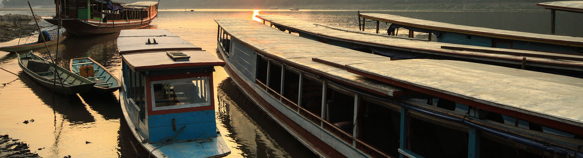 Wooden long boats moored together at sunset