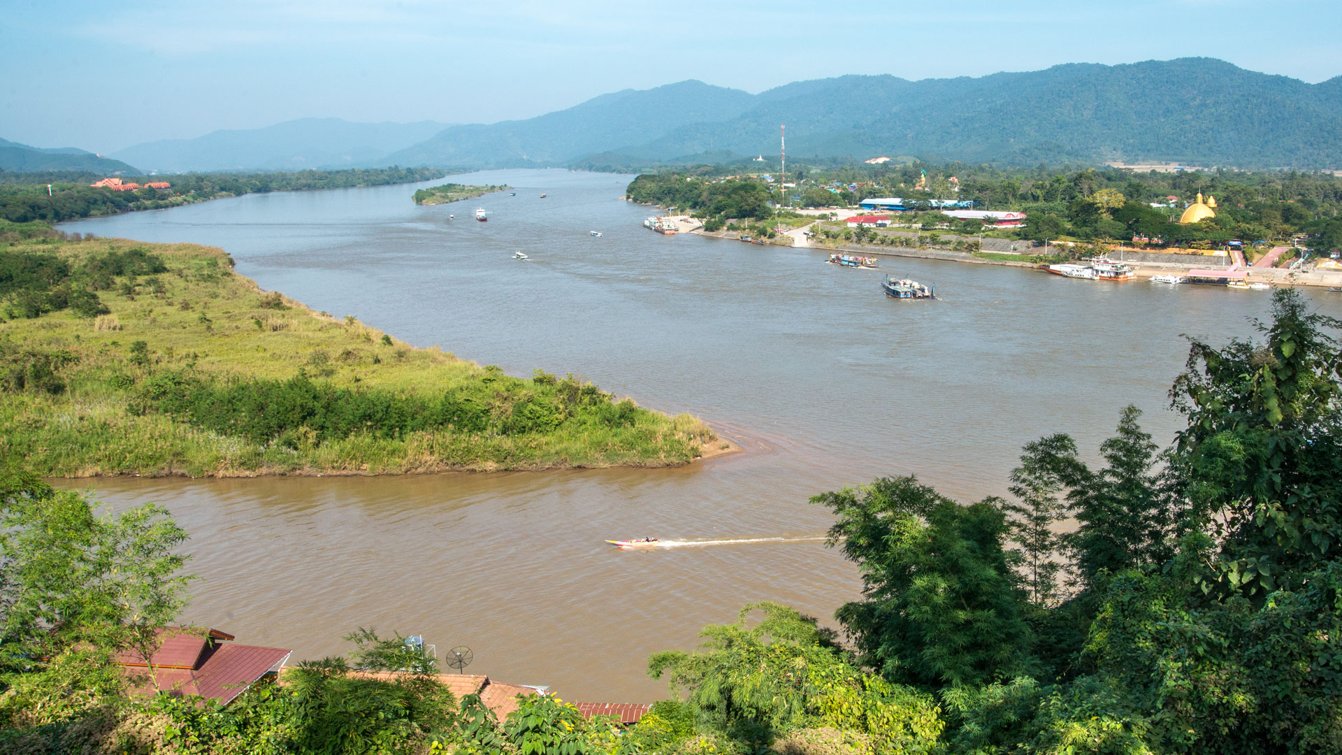 Wide bend of the Mekong between green banks and hazy mountains